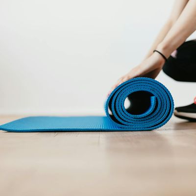 A neatly rolled yoga mat on a wooden floor.